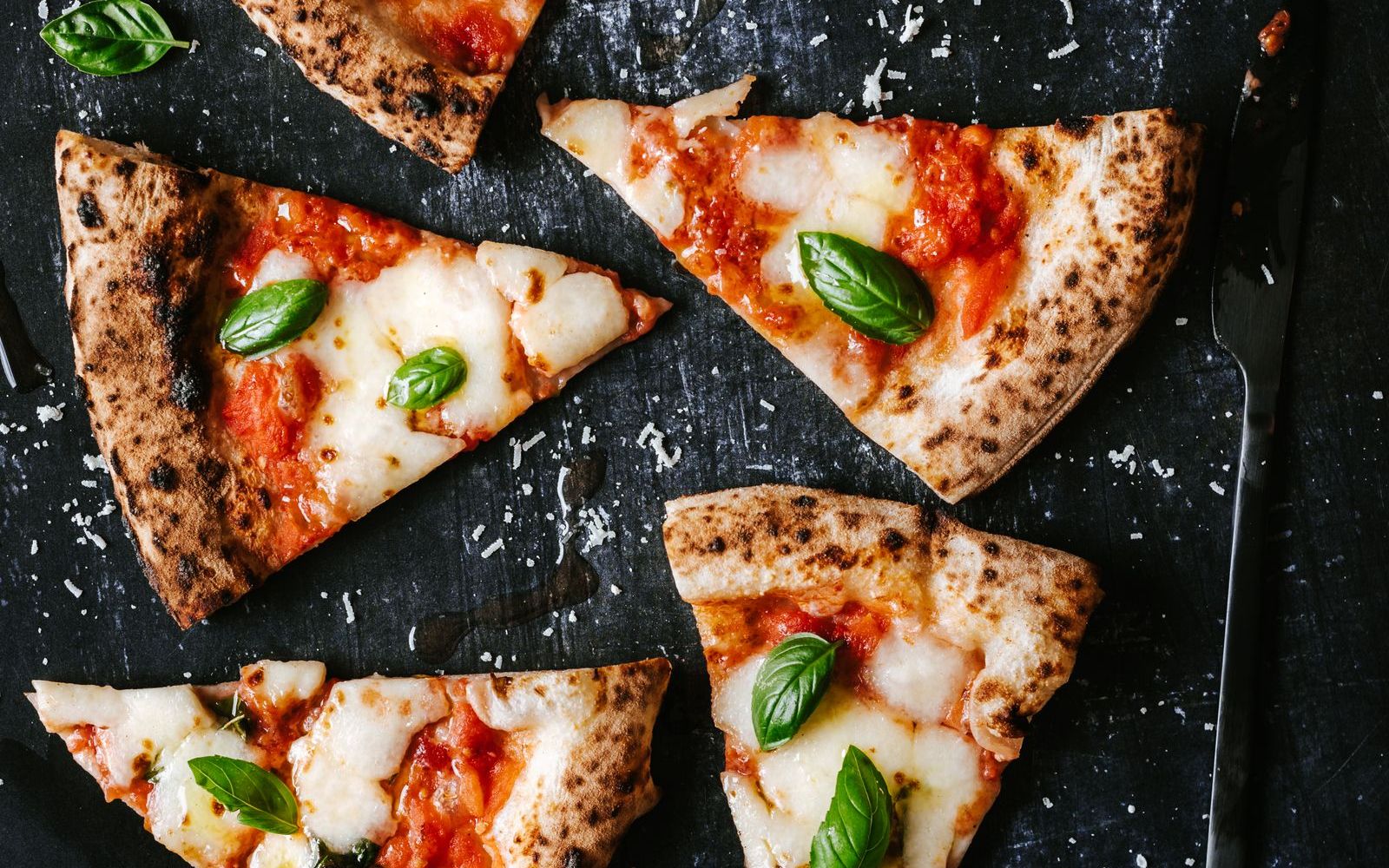 Margherita slices on black slate, the crust blistered